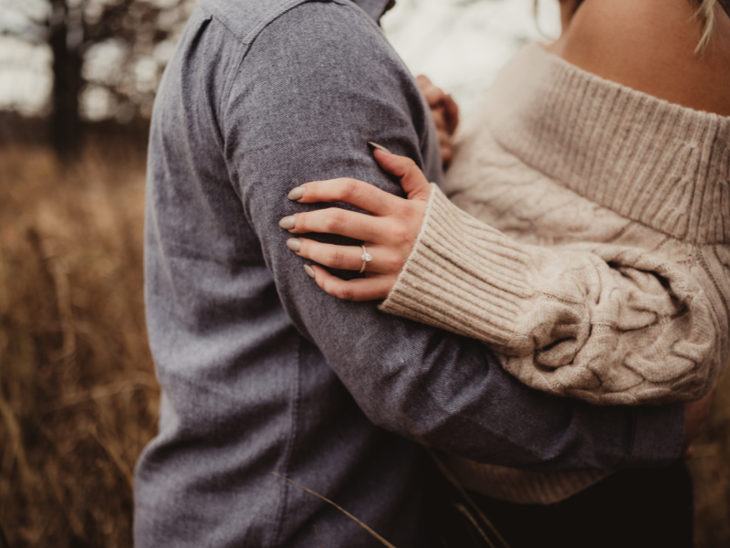 An engaged couple embraced in nature with a closeup of the engagement ring in the Smokies | Smoky Mountain Explorer